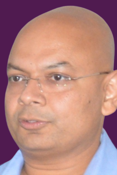 Divine-Alignment-Circle_processed A professional headshot of Rishi Sir, best coach, wearing glasses and a light blue shirt, set against a purple background.